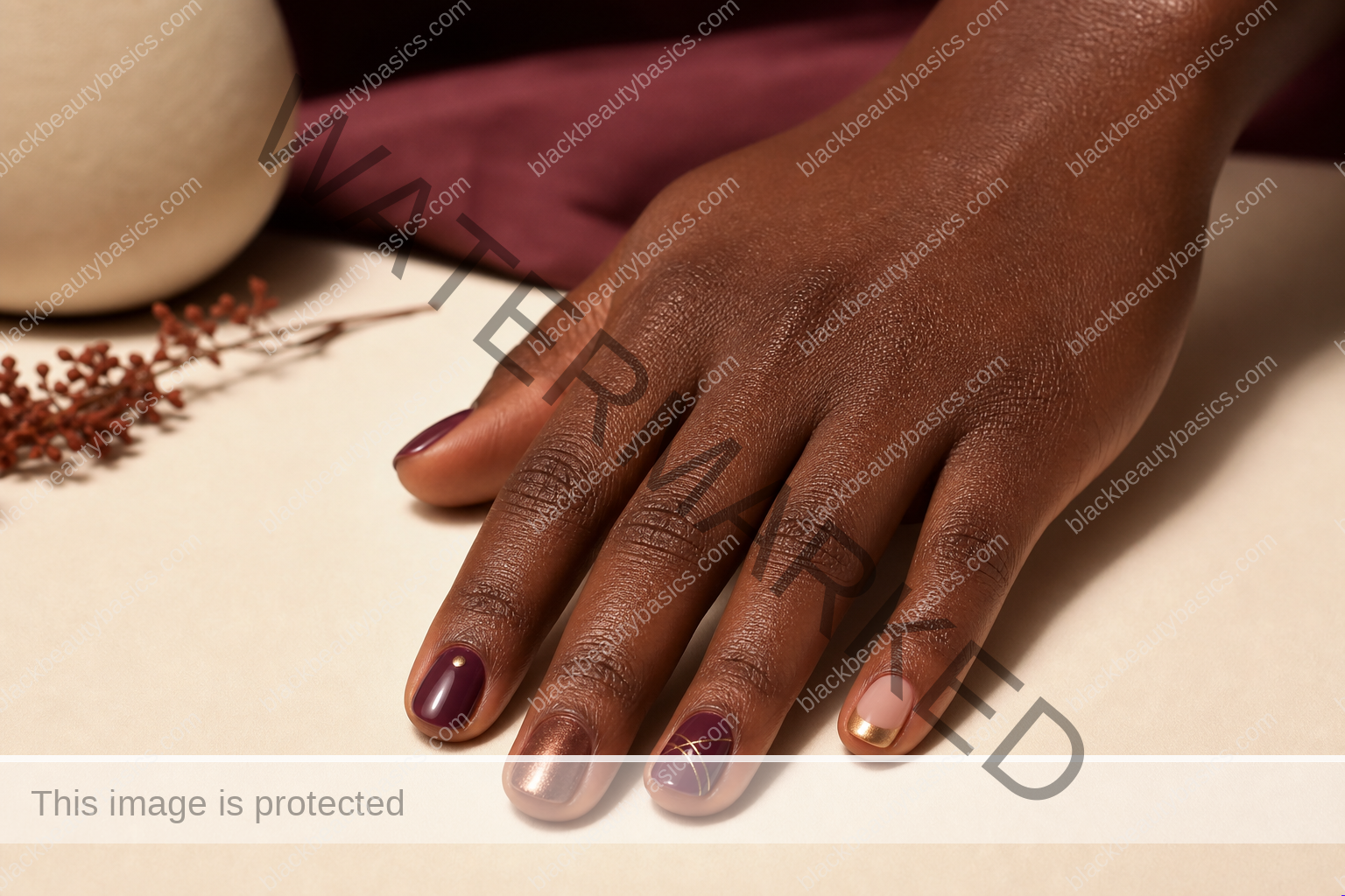 Rich-brown hand with five natural fingers wearing plum, bronze, and soft gold nail art
