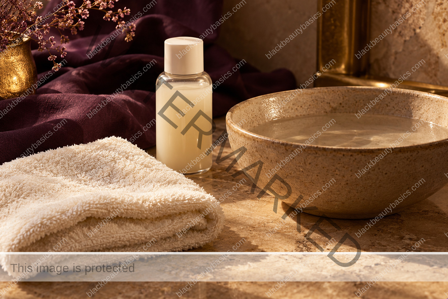 Soft ivory cloth, plain cleanser bottle and ceramic bowl on a warm stone surface